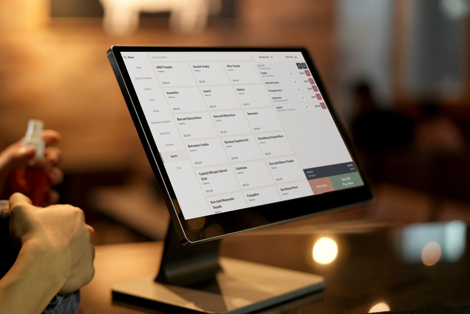 Order screen on a countertop terminal in a bar: spirits menu, an open ticket and a Pay Now button